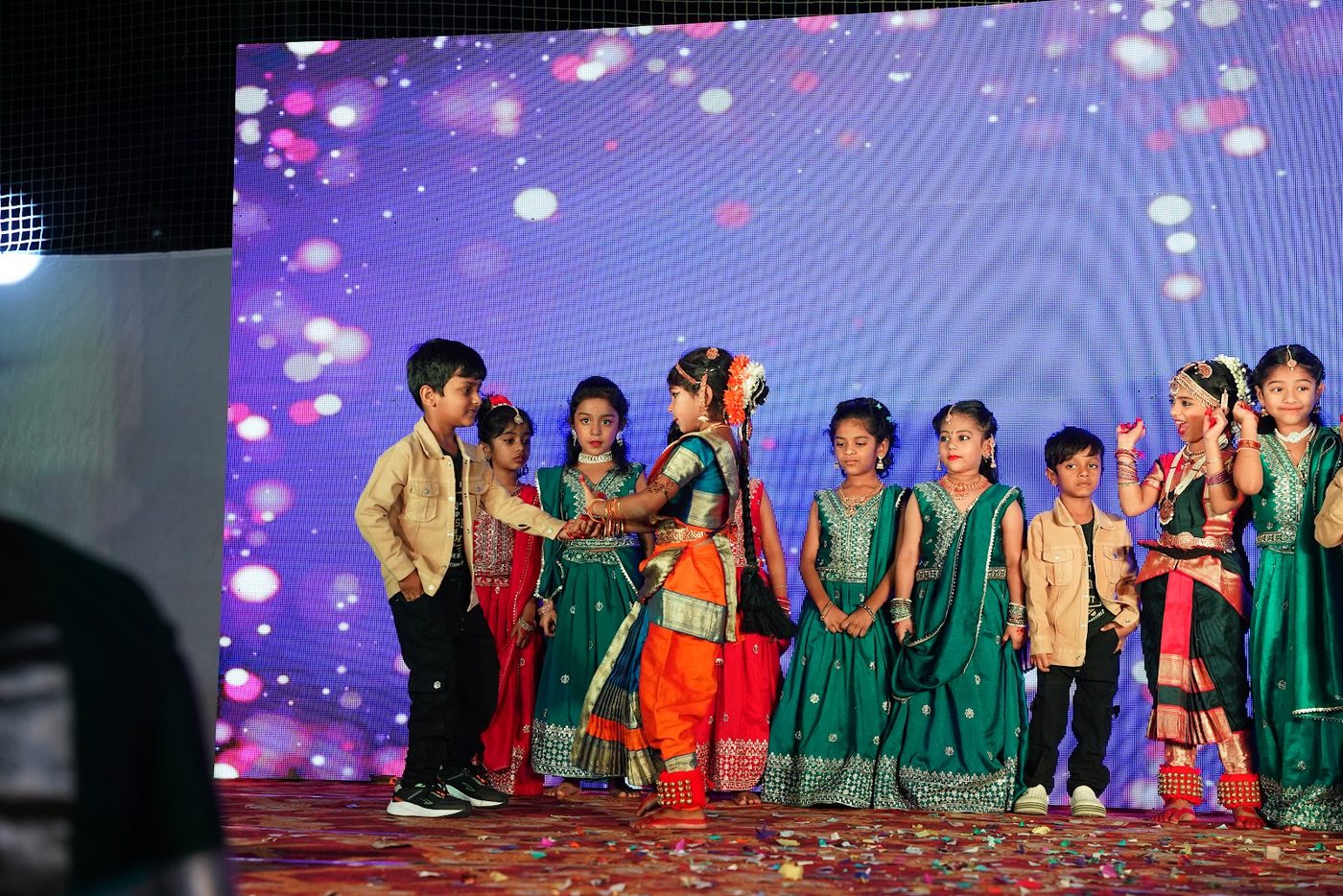 Students performing a folk dance in traditional dress at Little Ville Annual Day