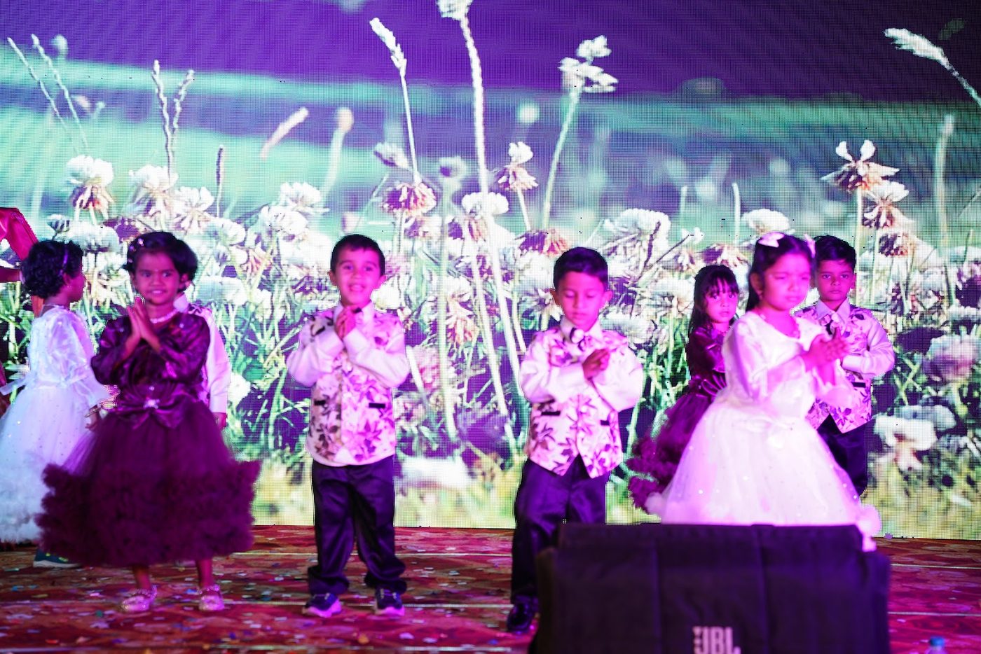 Little Ville students performing in front of a garden-themed backdrop at Annual Day