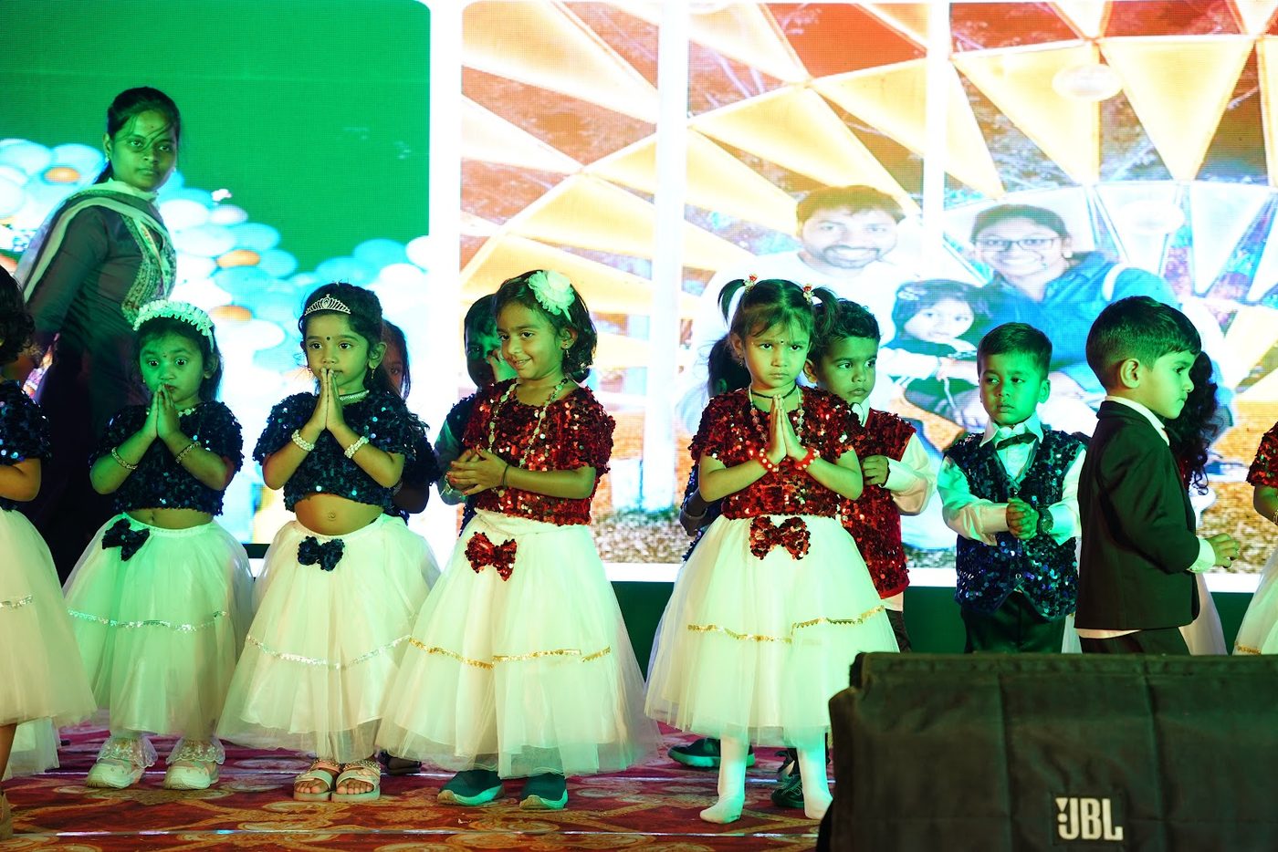 Students in formal winter costume performing on stage at Little Ville Annual Day