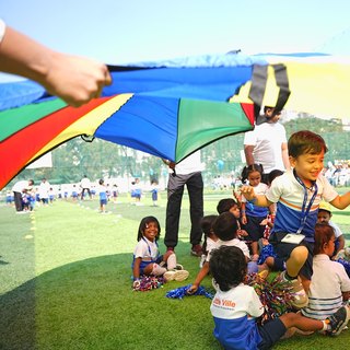 Little Ville children playing together with a colourful parachute at a school event